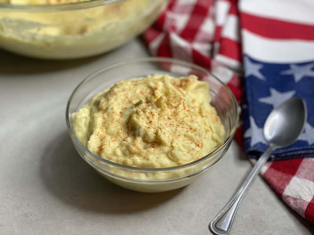 Bowl of potato salad flanked by american flag themed napkins and a spoon