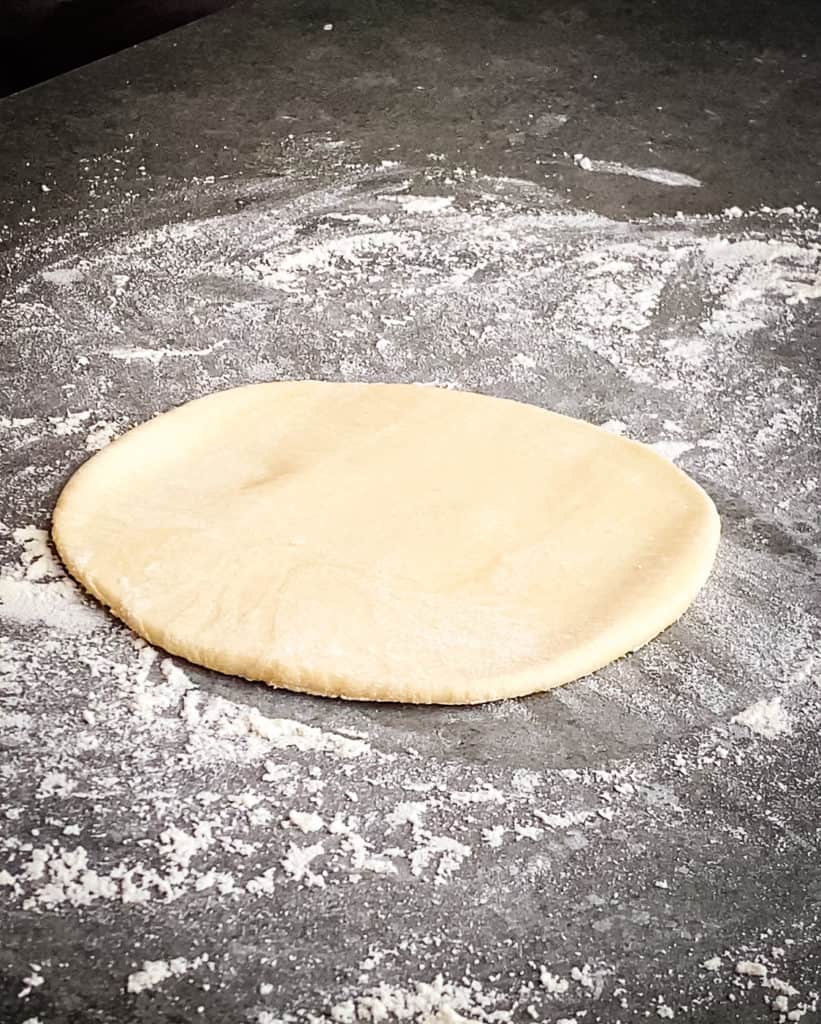 The dough which was turned 90 degrees has been rolled up and down and is now a circle