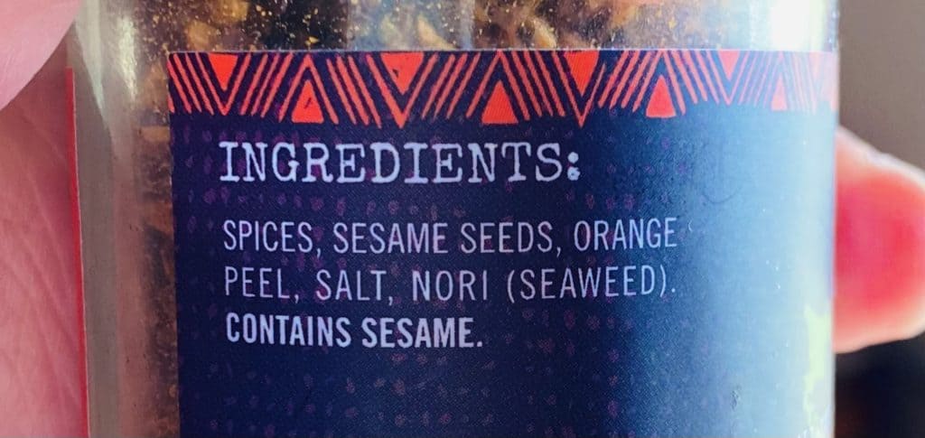 The ingredients list on my bottle of shichimi togarashi. It reads ingredients: spices, sesame seeds, orange peel, salt, nori (seaweed) contains sesame