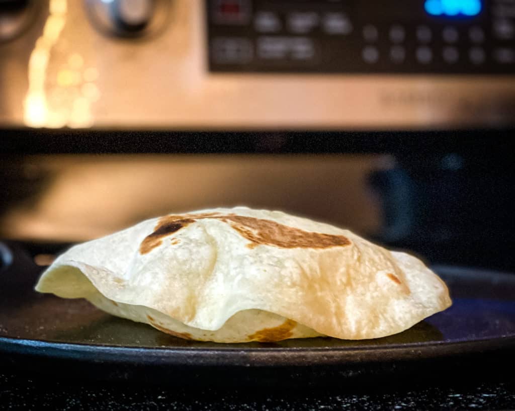 side view of a tortilla puffed up on top of the griddle