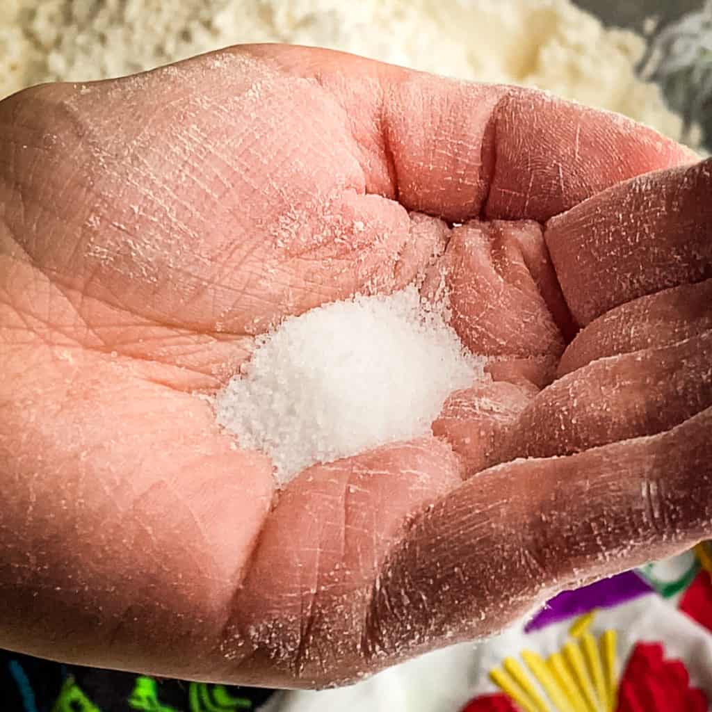 A small mound of salt in the palm of a white woman's hand