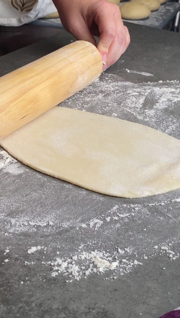 An elongated and thin dough with the rolling pin at the bottom
