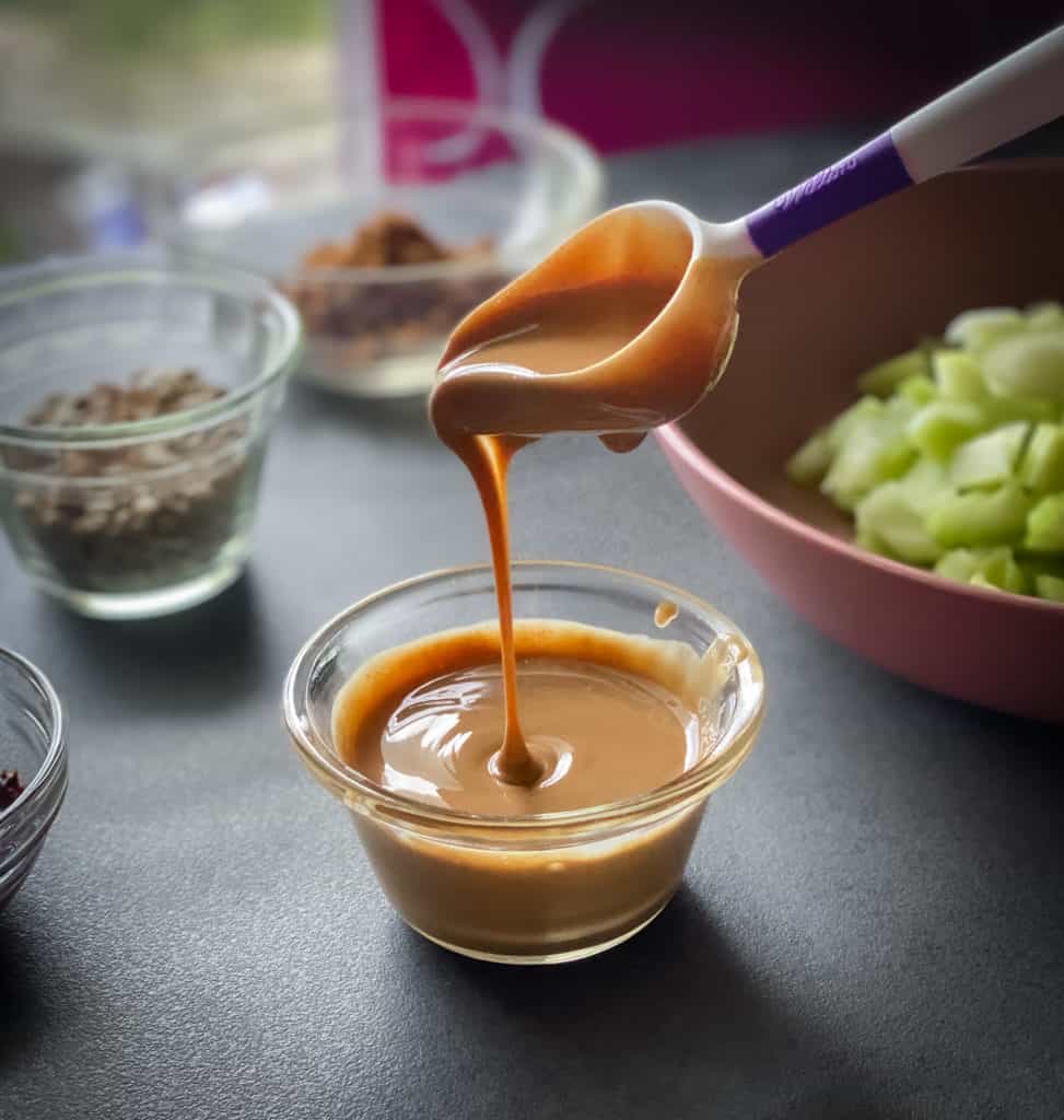 Melted peanut butter dripping from a spoon into a bowl full of More melted peanut butter