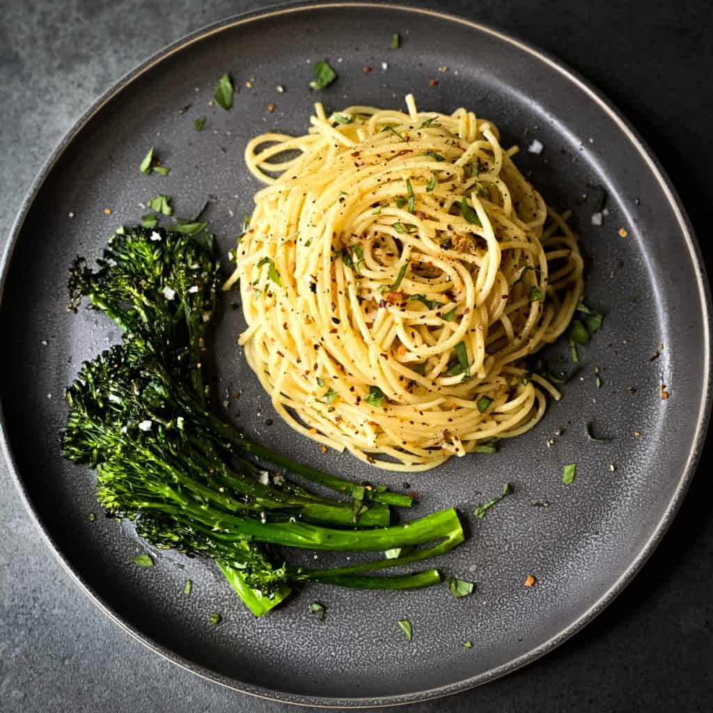 top down view of the grey plate with broccolini and a mound of spaghetti