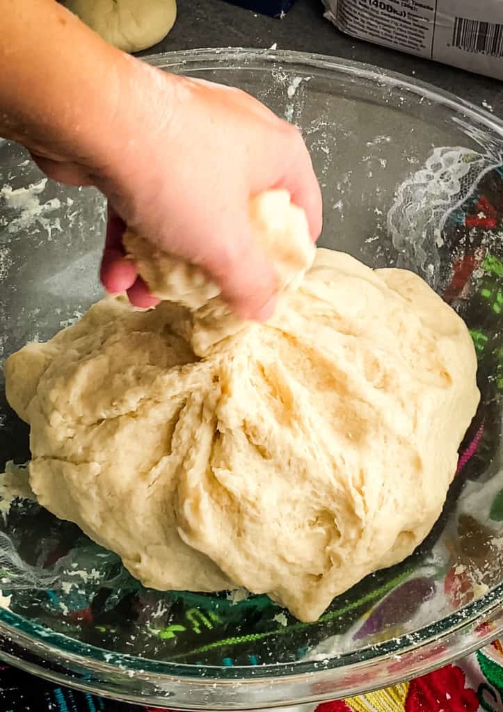 Twisting a golf ball sized piece of dough off of the large doughball
