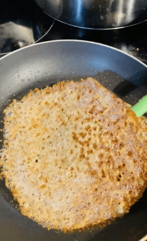 A crispy cream-and-brown cheese tuile in a nonstick pan