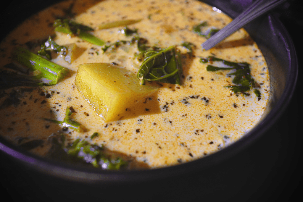 a black bowl filled with creamy zuppa toscana