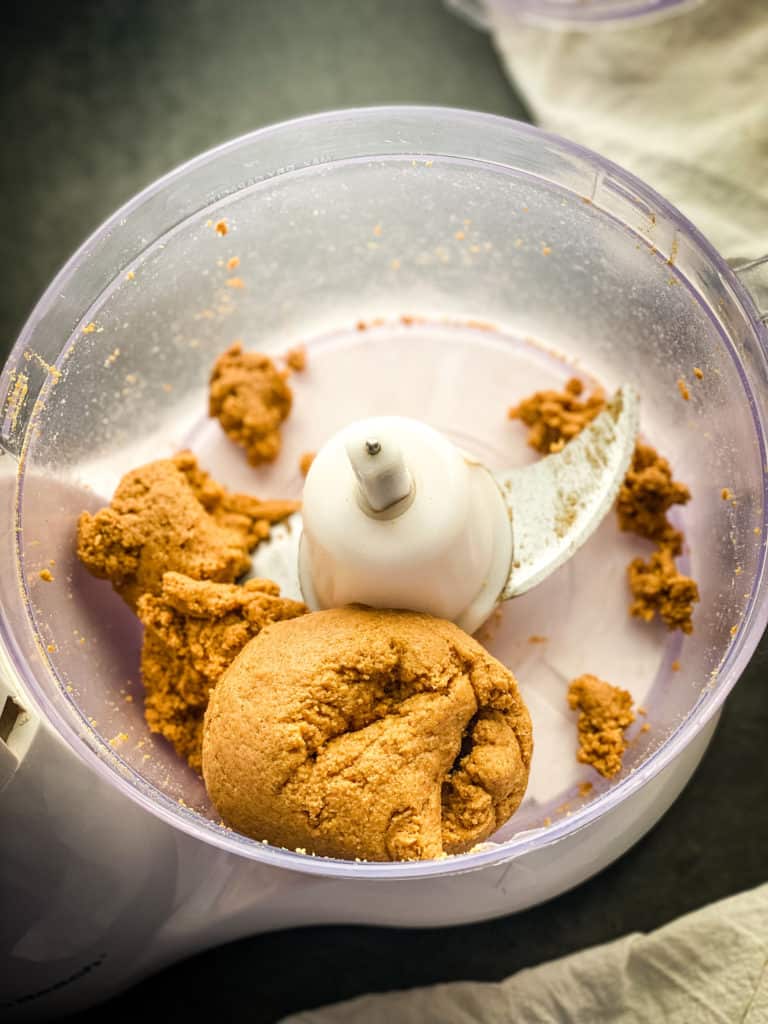 a doughball in the food processor bowl made from the graham cracker crumbs, butter, and water