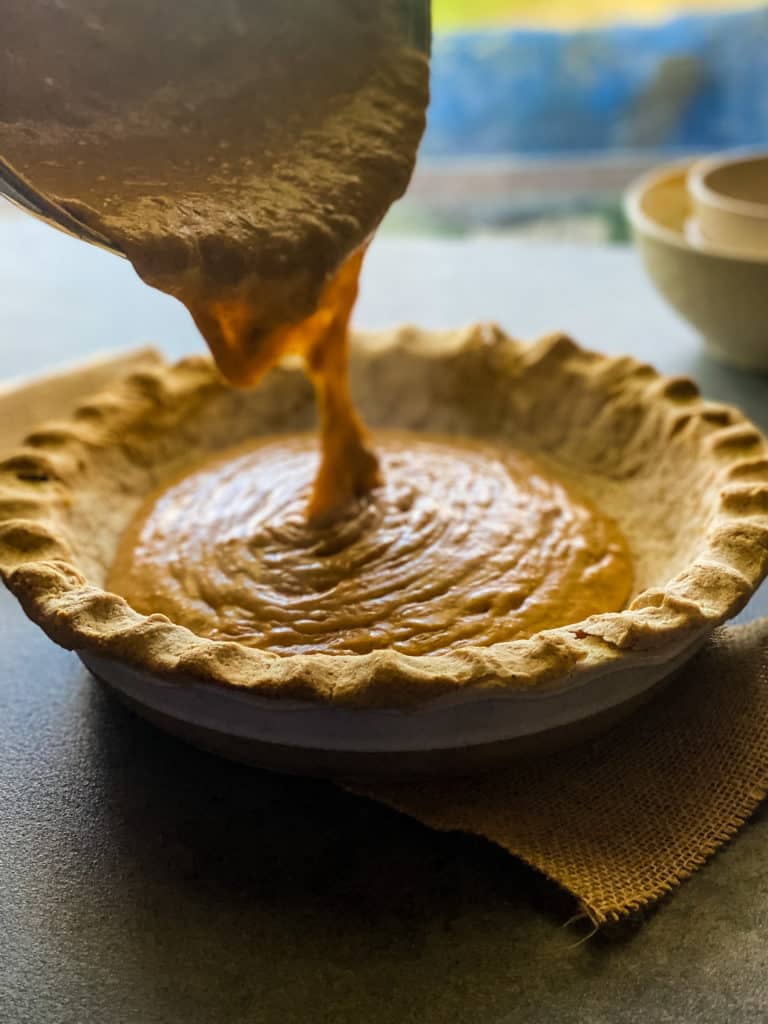 pouring pumpkin mixture into a prepared pie crust