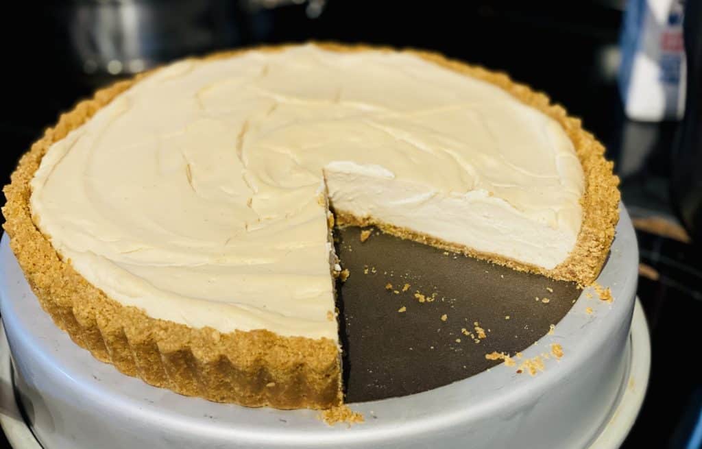 View of a cheesecake with a slice taken from it. You can see that the crust has kept its shape perfectly even after it was removed from the fluted tin.