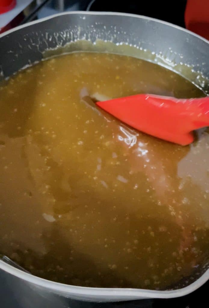 Thickened caramel sauce with a red spatula pressing down into it