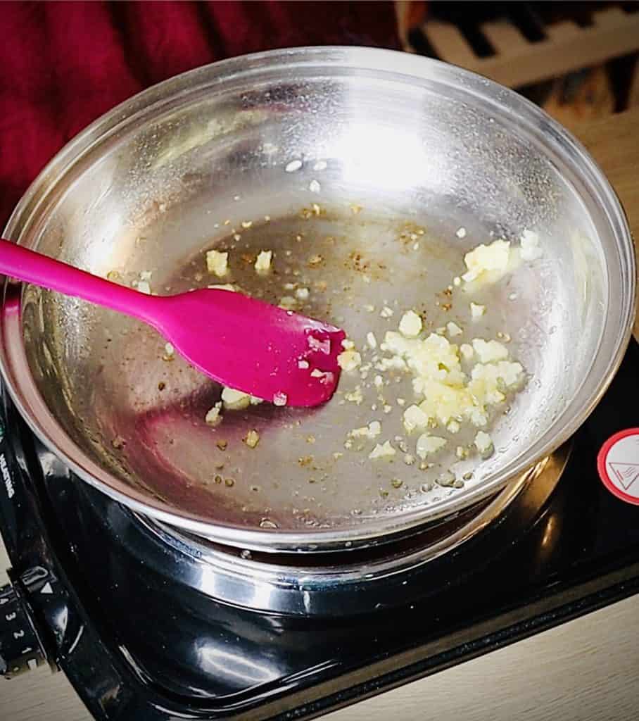 A small amount of minced onion and garlic in a stainless steel saute pan, barely starting to turn golden brown.